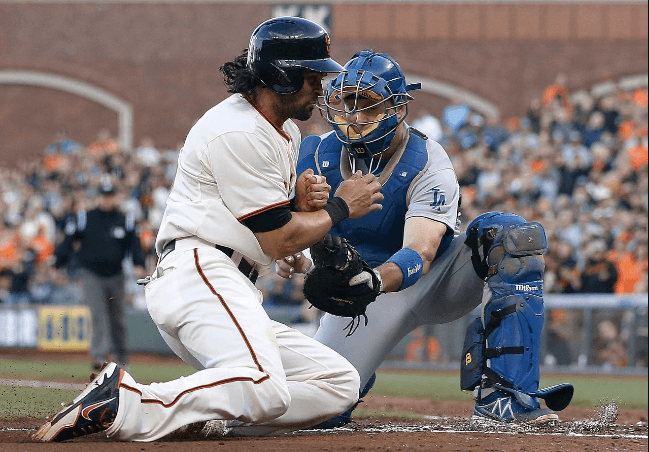 A picture of Angel Pagan sliding into homeplate while a Dodger tries to tag him out
