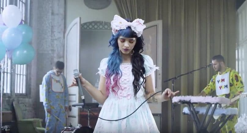A picture of Melanie Martinez holding a mic and looking down